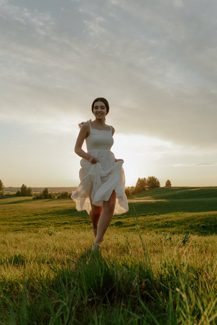 A woman joyfully runs through a sunny meadow, capturing the essence of summer freedom.